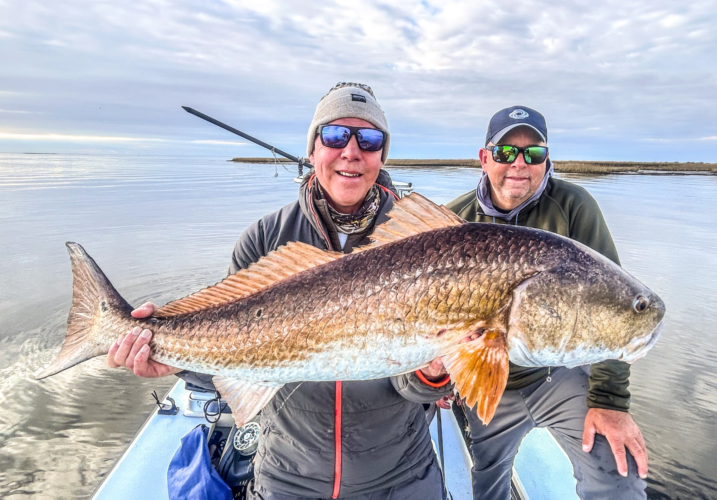 Smiling duo displaying impressive fishing trophy